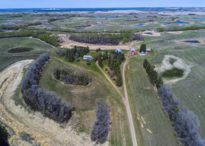 Aerial view of a farm featuring a red barn and a white house surrounded by fields and greenery.