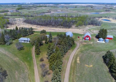 Bird's-eye view of a rural farm with a traditional barn and a cozy house set in a lush landscape.