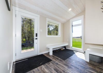 A charming small house with a welcoming deck, complemented by a vibrant tree, enhancing the peaceful setting.