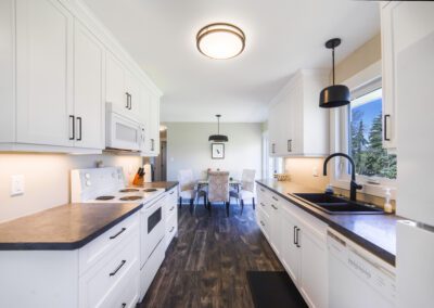 A well-organized kitchen with pristine white cabinets and a refrigerator, highlighting a fresh and airy culinary space.