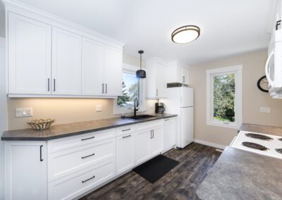 A modern kitchen featuring sleek white cabinets and a stainless steel refrigerator, creating a bright and inviting atmosphere.