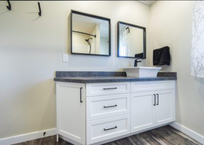A modern bathroom featuring a sleek sink and two stylish mirrors reflecting the contemporary design.