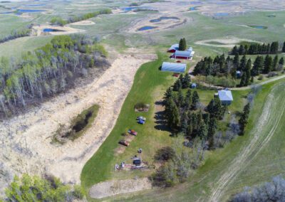 Bird's-eye view of a rural farm with a traditional barn and a cozy house set in a lush landscape.